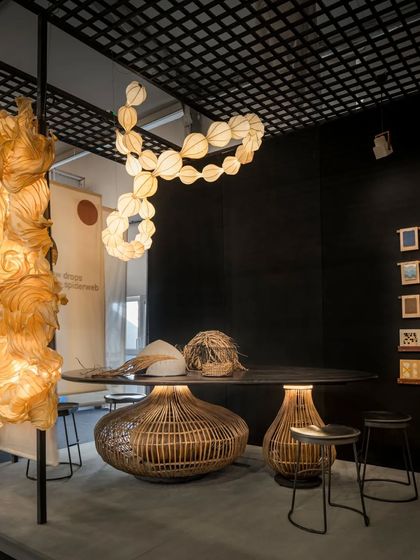 Another view of the central discussion area in the Oorjaa booth. The space was designed to be functional for conversations while being surrounded by beauty. The large, organic light fixture above mimics dewdrops on a spiderweb, continuing the nature-inspired theme throughout the booth.