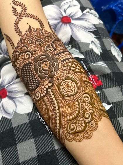 A close-up of the forearm portion of Leena's bridal henna, showcasing the intricate rose and paisley work.