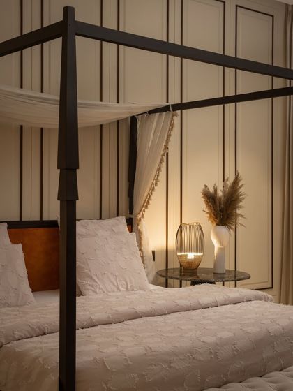 A four-poster bed brings a touch of classic elegance to this modern bedroom. The soft, layered textiles and warm, ambient lighting create a cozy and inviting retreat.