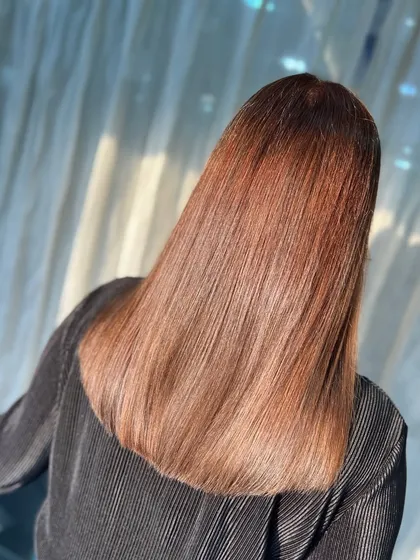 A dreamy transformation blending warmth, depth, and shine. This straight style shows off the smooth gradient from a darker root to lighter, coppery ends.