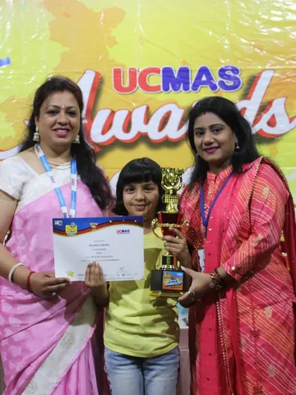 A young winner proudly holds her trophy and certificate at the NLC Awards Ceremony. Our instructors and team are always present to share in these moments of achievement.