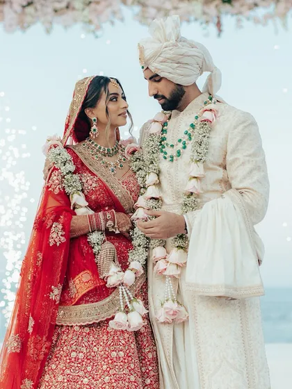 A quiet moment of connection between the bride and groom at their seaside wedding in Oman. The stunning red lehenga against his ivory sherwani, with the ocean behind them, is a memory frozen in time.
