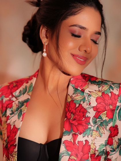 A close-up of Karunya's makeup, showing the soft, shimmery eyeshadow and glossy lip. The look is fresh, modern, and glamorous.