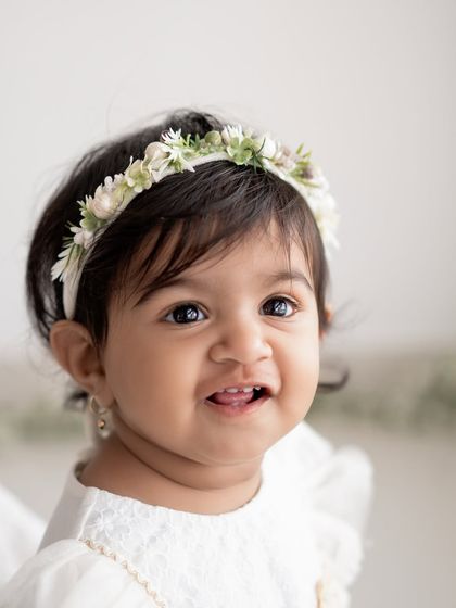 A close-up of a baby girl with a sweet floral headband.