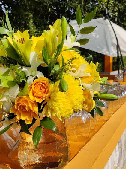 A close-up of the floral arrangements at the bar, featuring a mix of yellow roses, lilies, and chrysanthemums in glass vases.