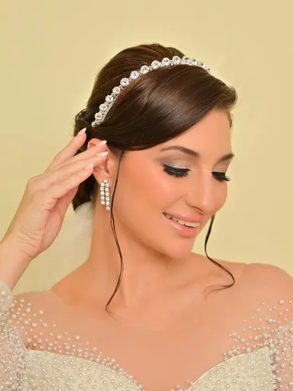 A gentle smile from the bride, her makeup looking flawless. The elegant updo is adorned with a simple, sparkling tiara.
