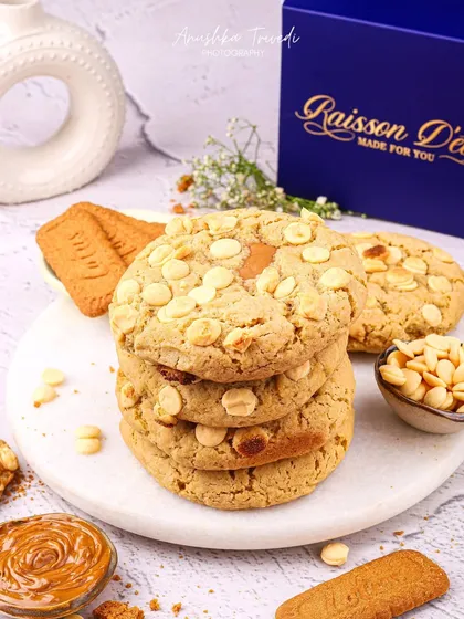 A stack of white chocolate and Biscoff cookies. The styling is bright and clean, highlighting the textures of the cookie and the ingredients.
