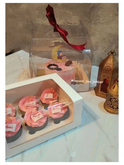 A lovely Eid gift set featuring a pink bento cake and a box of matching pink cupcakes with custom name toppers.
