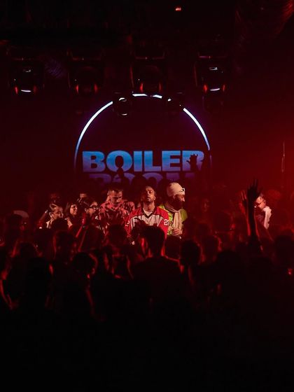 A still from a Boiler Room performance, capturing the intense red lighting and the packed crowd.