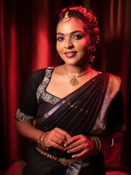 A model posing in a black saree, with dramatic lighting that highlights her features.