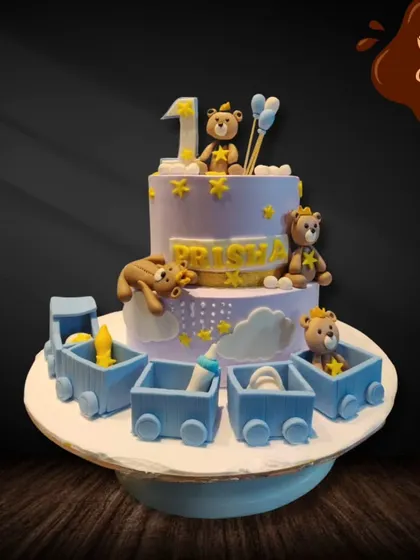 All aboard the birthday express! This two-tier cake for a first birthday features a cute train filled with teddy bears and baby items, creating a playful and adorable theme for the celebration.