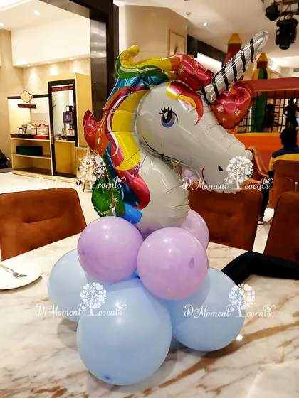 A unicorn head foil balloon on a pastel balloon base creates a magical centerpiece for a unicorn-themed party table.