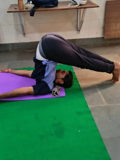 A student performs Halasana (Plough Pose) during a class. I focus on proper form and technique to help students achieve deep stretches and prevent injury, a key skill for any yoga teacher.