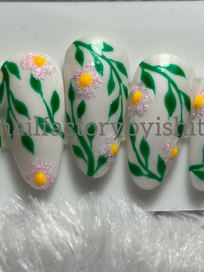 A set of hand-painted press-on nails with a delicate green vine and flower design. Learn to make these in my nail art course.