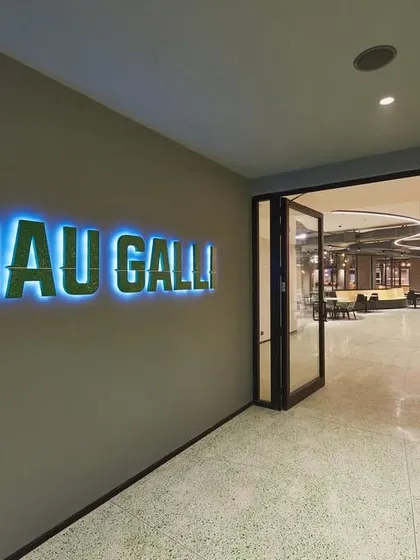 Another view of the "Khau Galli" entrance, with backlit signage that creates a vibrant glow. This leads into a large, dynamic cafeteria space.