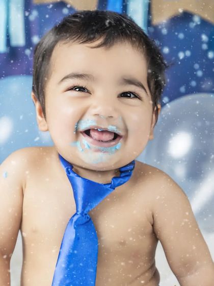 A close-up of this birthday boy's happy, cake-covered face. The blue tie adds a touch of dapper charm to the messy fun.