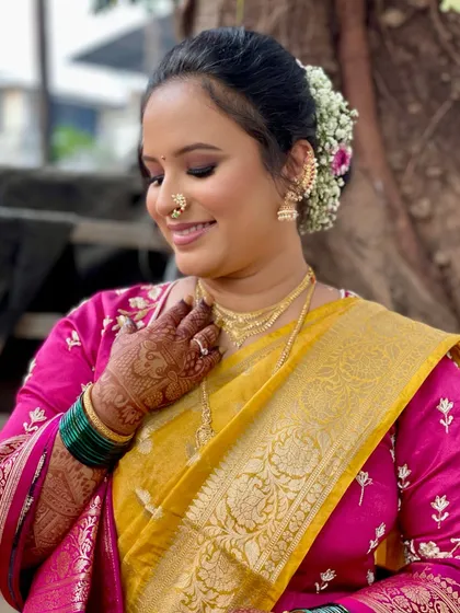 A close-up showing the beautiful floral bun and the soft, smiling expression of the bride. The makeup enhances her features without looking heavy.