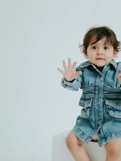 For a timeless look, I offer minimalist first birthday portraits. This simple, clean setup with a classic denim jacket puts all the focus on your baby's adorable personality and expressions.