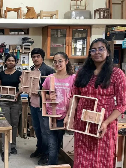 A group of interior design students proudly displaying the complex shelf designs they built in a single day.