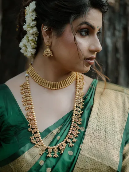 A detailed close-up of the bride's traditional gold jewelry and her elegant profile. This shot emphasizes the beautiful details of her bridal look.