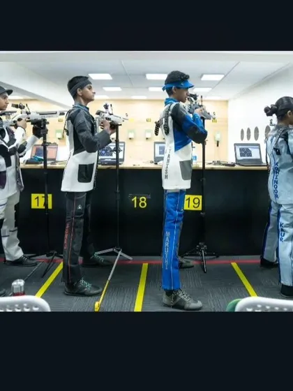 Young shooters in professional gear, standing with precision and focus, ready for their turn to compete in the national tournament.