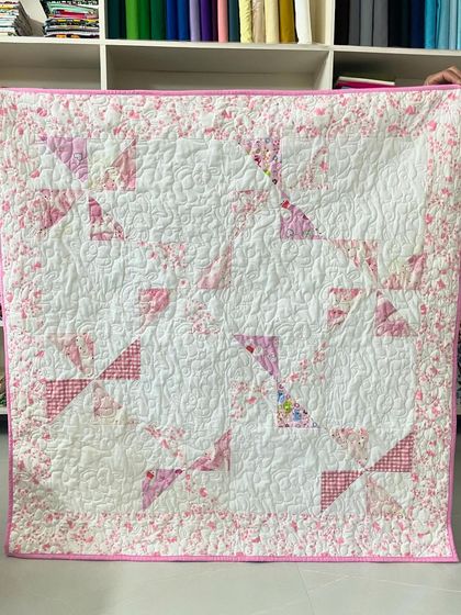 A lovely baby quilt in pink and white, with a pinwheel block design.