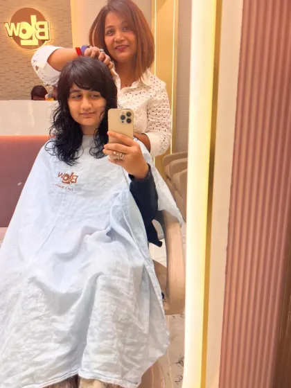 A client taking a mirror selfie of her new haircut. The fresh layers and bangs give her a modern and chic look.