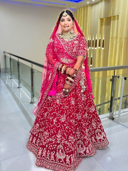 A full-length shot of the same bride, showcasing her magnificent pink lehenga with intricate silver embroidery.
