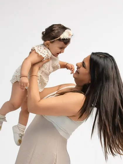 A mother lifts her baby girl high, both sharing a look of pure happiness. These dynamic, playful shots capture the energy and joy of your family bond.