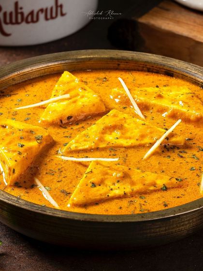 Paneer-e-Rubaruh, a vegetarian signature dish, with a focus on the soft paneer triangles in a creamy sauce.