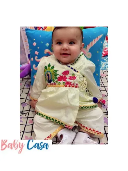 A sweet baby boy in our off-white angrakha-style kurta with peacock embroidery. This traditional outfit is a comfortable and elegant choice for any festive puja.