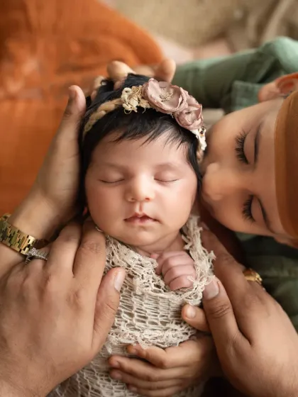 A tender moment as a big brother gently kisses his newborn sister's cheek. Sibling photoshoots, especially with a new baby, are so precious for capturing the start of a lifelong bond.