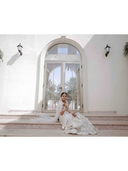 A beautiful shot of the bride in her silver saree, seated on the steps of a villa.