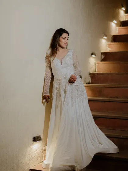 The bride in a beautiful white gown, posing on a staircase. Her elegance and poise are perfectly captured in this sophisticated shot.
