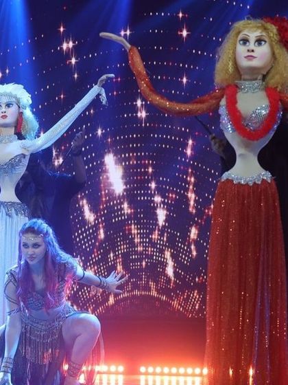 A full stage view of the belly dancer puppet performance. The combination of human dancers and puppet dancers creates a unique and layered visual spectacle.