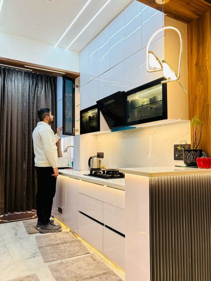 A final look at this beautiful modular kitchen at Prateek Laurel, featuring white high-gloss cabinets, a built-in oven, and a breakfast counter with a wooden finish.