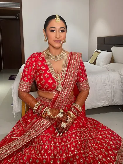 A classic bridal look for Kritika in a stunning red lehenga. The makeup is clean and flawless with defined eyes, paired with a sleek bun for a regal and polished finish.