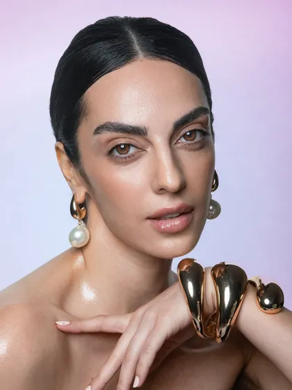 This final shot from the series brings together the glossy skin, bold brows, and statement jewellery for a complete, high-end beauty look.