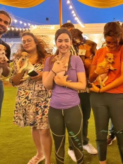 A group of participants at an outdoor event, each holding an adorable puppy and smiling for a group photo.