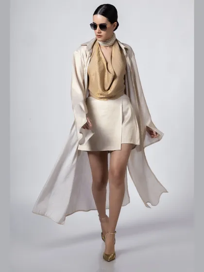 An international model walks towards the camera in a sophisticated beige and cream outfit, capturing a sense of movement and high-fashion elegance.