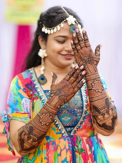 A joyful bride showing off her full mehendi during her ceremony.