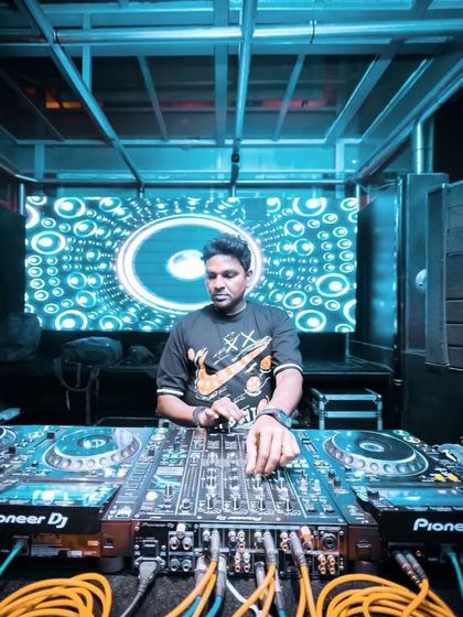 A wide shot of my DJ setup at a club, showing the full Pioneer console and the vibrant LED screen behind me.