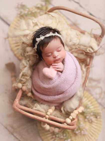 Sweet baby Eva. The soft pink wrap, tiny heart prop, and delicate headband come together for a truly lovely and heartfelt portrait.