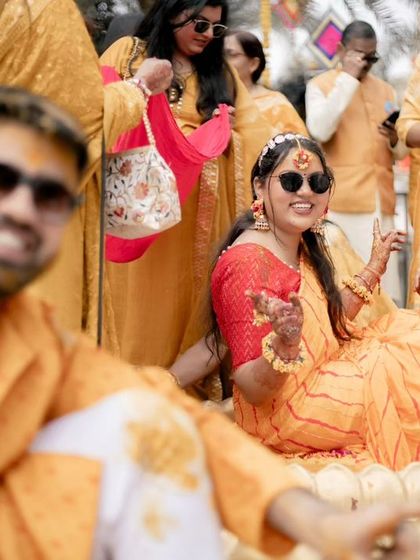 A fun, candid shot of the bride, Divyanshi, surrounded by her friends and family during the Haldi rituals.