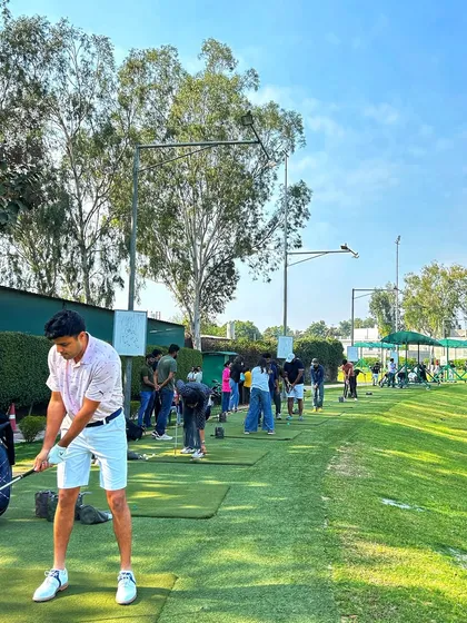A young golfer in white shorts takes a powerful swing on the mat, showing great form.