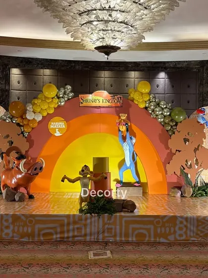 A wide shot of the complete stage, showing the scale of the backdrop, life-sized characters, and balloon garlands.
