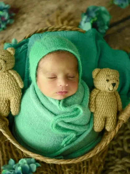 Two little bears guarding a sleeping baby. This setup uses crocheted teddy bears to add a classic, cute element to the newborn basket photo.