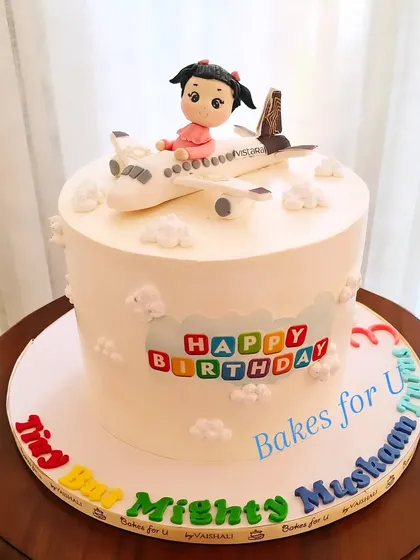 A Vistara airplane-themed cake for a little girl who loves watching planes. The cake features a handcrafted fondant airplane with a cute girl figure sitting on top.