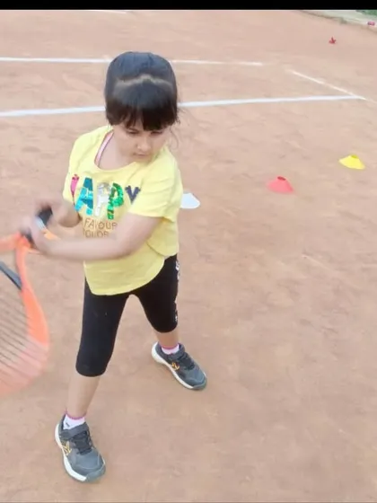 This young girl is in the middle of her forehand swing, showing great form and follow-through for her age.