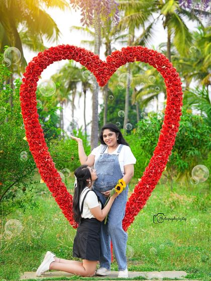 A fun and playful outdoor shot with a friend, who is kneeling to listen to the baby bump in front of our red floral heart prop.